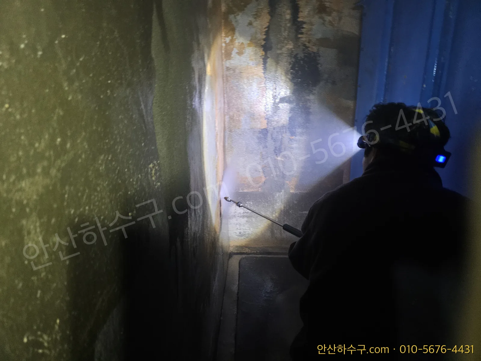 헤드랜턴을 켜고 집수정 벽면을 고압세척하는 모습
