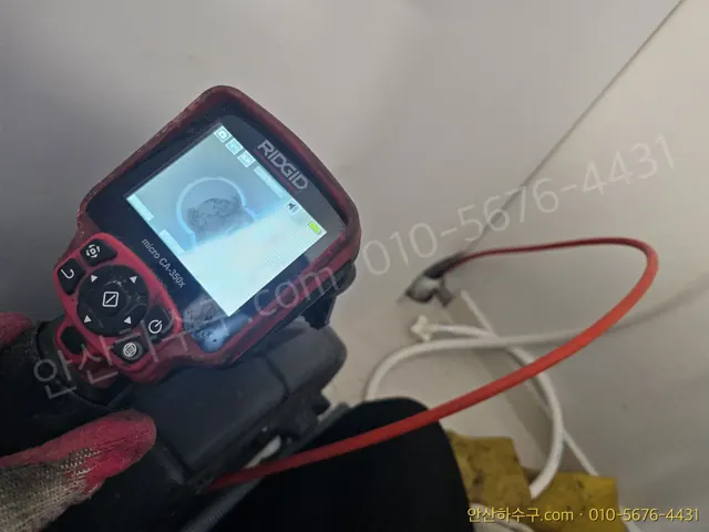 안산 고잔동 아파트 세탁실에서 배관 내시경 모니터로 하수구막힘 원인을 확인하는 안산하수구 작업 현장