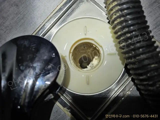 안산 선부동 화장실 바닥 배수구를 열어 석회로 막힌 내부를 확인하는 안산하수구 작업 현장