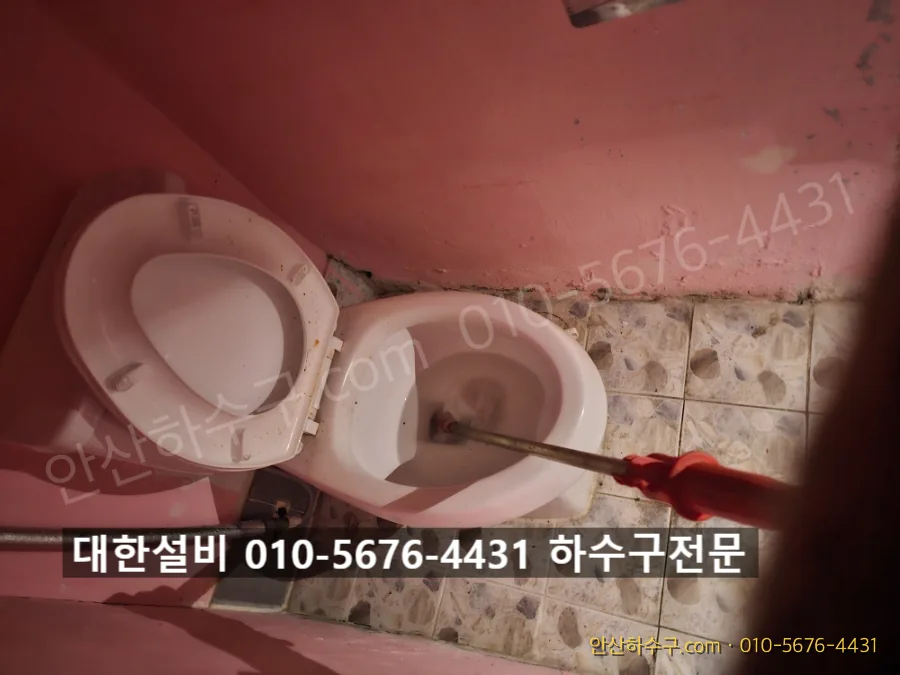 자리를 잡은 관통기로 막힌 변기 배관을 뚫는 작업